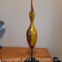 Front view of the blown glass shore bird decoy on a wooden surface with metal base visible.