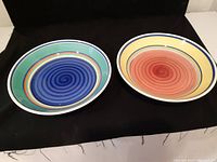 Two vintage Italian ceramic pasta serving bowls side by side showing different color spiral designs.