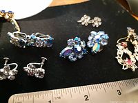 Close-up of six pairs of sparkly earrings highlighting styles and rhinestone colors, some blue, pink, and clear