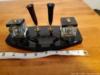 Front view of antique black onyx desk set showing glass inkwells and brass quill holders on black onyx base with ruler for scale.
