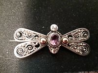 Front view of the antique sterling silver butterfly brooch showing filigree detail on wings and central amethyst stone.