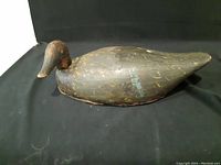 Photo of the full side view of the wooden decoy duck showing its shape and painted surface.