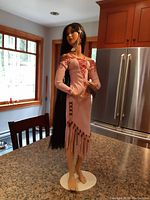 Full front view of the figurine showing the entire stature on a round white base, detailed dress and long hair.