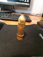 Full frontal image of the vintage bullet-shaped lighter on a black surface in front of a computer keyboard and mouse.