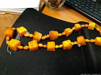 Photo showing full necklace with various chunk amber beads in geometric shapes like cubes and irregular forms laid out flat.