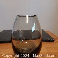 Front view of the oval smokey grey glass vase with smooth top rim and rounded shape.