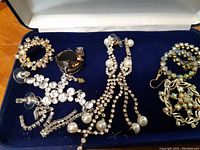 Blue velvet-lined box displaying vintage costume jewelry set consisting of six pieces including earrings and brooches with rhinestones and faux pearls.