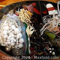 Overview of mixed costume jewellery including beads, necklaces, earrings, and brooches in a metal tray showing variety and condition.