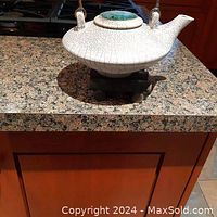 Front view of Shino teapot on wooden stand on countertop