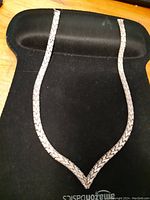 Full view of the silver chain necklace displayed on a black background to show its shape and design