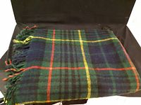 Folded vintage tartan wool throw showing classic plaid pattern and fringed edges.