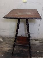 Front angled view of the antique wooden side table showing turned legs and surface wear on top.