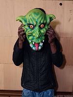 Image of person holding green demon mask showing size and front details