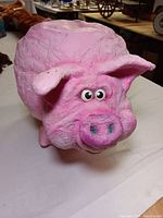 Front close-up view of the pink pig sculpture showing the face, eyes, snout and ears.