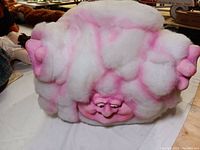 Front view of the pink cloud man sculpture showing face and fluffy cloud body.