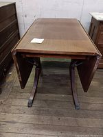 Top view of the vintage wood drop leaf dining table with leaves raised, showing table surface and brass claw feet.