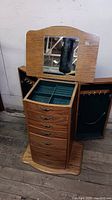Front view of oak wood jewelry chest with open top compartment showing mirror and green felt lining with multiple sections.