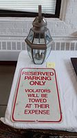Photo showing the outdoor lantern metal light fixture and reserved parking sign on a white surface, indicating the lot contents.