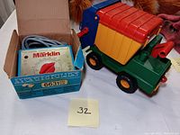 Marklin model train transformer in original blue and white box next to colorful plastic toy truck