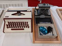 Vintage Marx manual typewriter and Polaroid Automatic 230 Land Camera with flash on a wooden tray