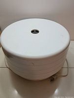 Food dehydrator fully assembled with four stacked trays and a solid top cover, showing electric power cord and plastic body.