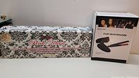 Photo showing Pink Zebra hair accessory box with floral damask black and white pattern and pink lettering.