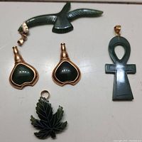 Overview of 5 jade pendants showing bird, hearts, ankh, and leaf designs