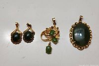 Four jade pendants arranged on white background, showing rope detail and pendant sizes
