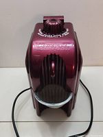 Front view of maroon Jewel Jet steam cleaner showing catch basket and control knob on top.