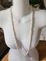 Full view of the pearl necklace draped on a white mannequin bust showing length and pearl size.