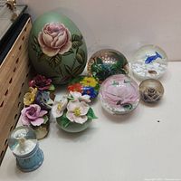 Overview of all items including green egg-shaped floral log figurine, multi-color floral figurine, snow globes, glass orbs and ring box