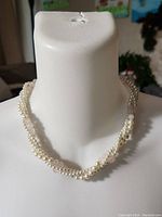 Photo of a faux pearl necklace in twisted strand design shown on white display bust.