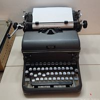 Front view of the dark gray Royal brand typewriter showing paper loaded and mechanical carriage return lever.