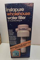 Box showing front of Instapure Wholehouse Water Filter Model TF-200 featuring protective features and filter illustration.