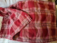 Close up of a red plaid wool blanket corner showing Air Canada embroidery