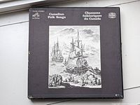 Top view of the black and white illustrated cardboard box cover showing sailing ships and people at a shore, Canadian Folk Songs / Chansons folkloriques du Canada.