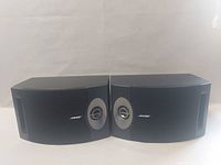 Pair of Bose 201V speakers front view showing black grille with Bose logos and circular drivers with silver accents.