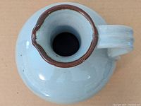 Top down view of the jug showing the narrow neck and brown rim on the spout.