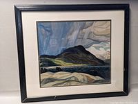 Framed print of a stylized landscape with a black wooden frame showing chips and scuffs.