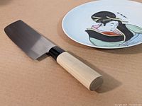 Nakiri knife and decorative dish shown on cardboard surface for scale and detail