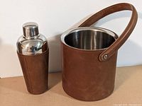 Side view of the leather wrapped cocktail shaker and ice bucket showing the handle and cap.