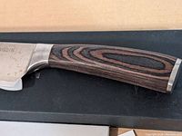 Close-up side view of the wooden handle showing grain detail and metal bolster with Paudin marking on the blade near handle.