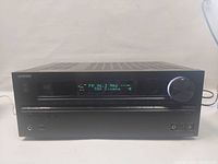 Front view of Onkyo AV receiver showing display, buttons, and volume knob.