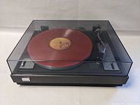 Front view of Sansui FR-1080 turntable with closed dust cover and red vinyl on platter
