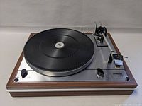 Angled front view showing wood veneer plinth, aluminum top plate, platter and tonearm