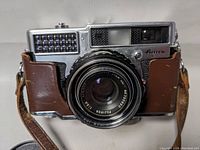 Front view of Fujica 35 SE camera showing lens with Fujinon branding, viewfinder, flash grid, and leather body covering.