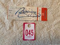 Photo of the full hockey ticket signed by Bobby Hull with numbered entry pass below.