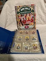 Blue binder opened to show hockey cards in plastic pages, and the 'Hockey Immortals 1911' book standing behind.