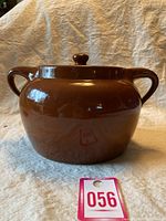 Front view of the brown glazed ceramic bean pot with lid and side handles, showing the Sunburst Ceramics Ltd stamp.