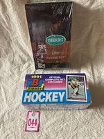 Photo of unopened 1991 Parkhurst French hockey card box with seals, alongside unopened 1991 Bowman complete hockey card set in blue box.